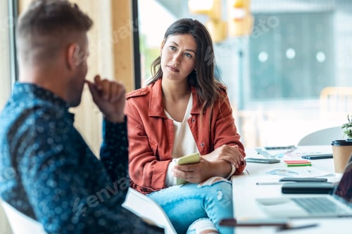 Preview: Smart business people working together with laptop while talking in the coworking place.