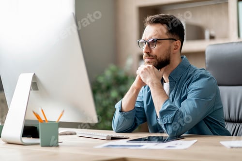 Preview: Portrait Of Pensive Young Businessman In Eyeglasses Looking At Computer Screen