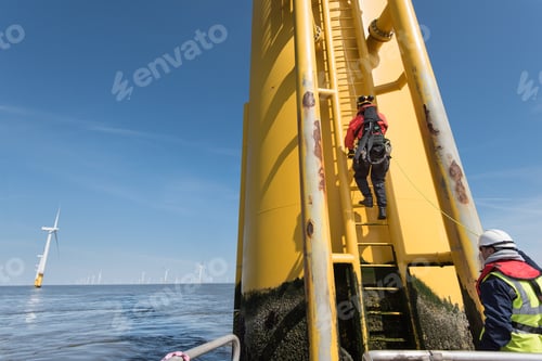 Preview: Engineers climbing wind turbine ladder from boat at offshore windfarm