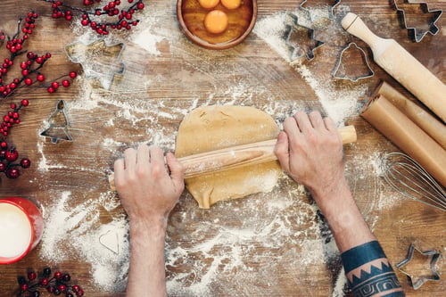 Preview: top view of person with rolling pin preparing gingerbread dough for christmas cookies