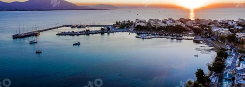 Preview: Panoramic view of boats moored at a harbor of against buildings on a beach at sunset
