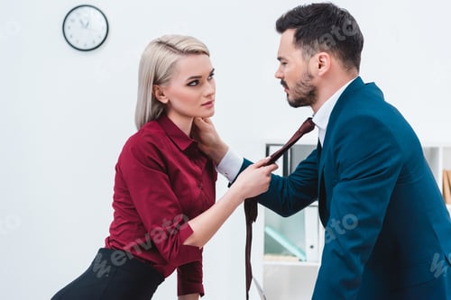 Preview: seductive young couple of business colleagues flirting and looking at each other in office