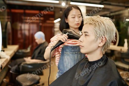 Preview: Young Asian Man in Beauty Salon with Hairstylist Drying Bleached Hair