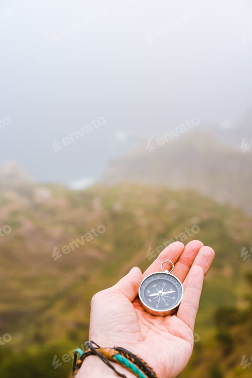 Preview: Palm with compass. Concept of figure out right direction. Haze valley and mountains in background