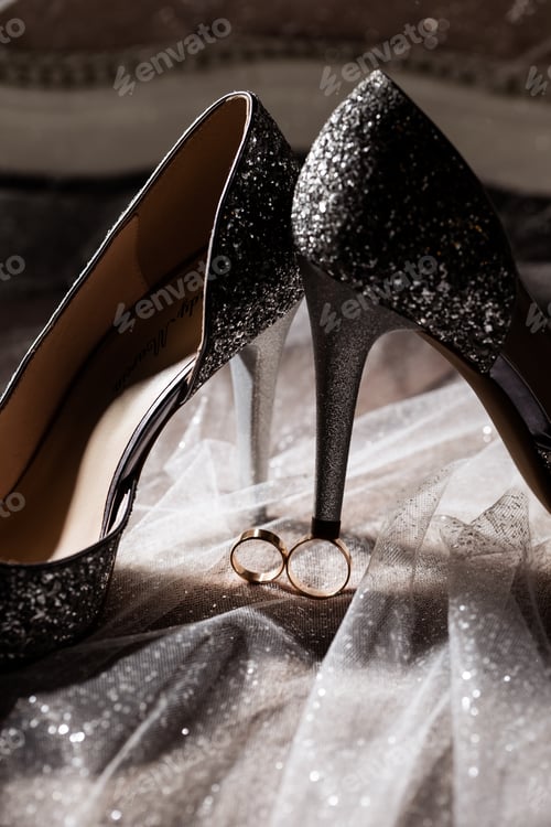 Preview: Golden rings of the newlyweds between white shoes with heels. Precious rings of the bride and groom