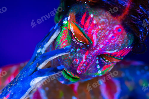 Preview: Body art glowing in ultraviolet light. Body art on the body and hand of a girl glowing in the