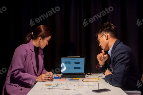 Preview: Two people are sitting at a table with a laptop in front of them