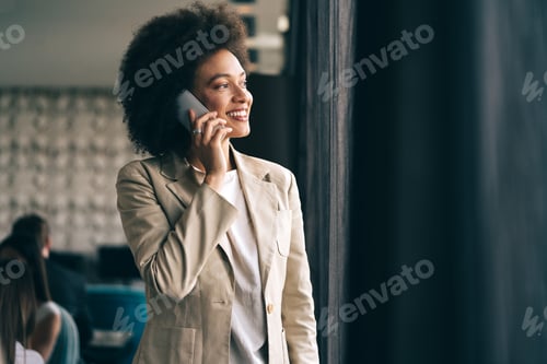 Preview: Beautiful african corporate worker talking on mobile phone