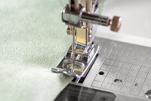 Preview: Modern Sewing Machine Presser Foot With Green Fabric And Thread, Closeup, Macro