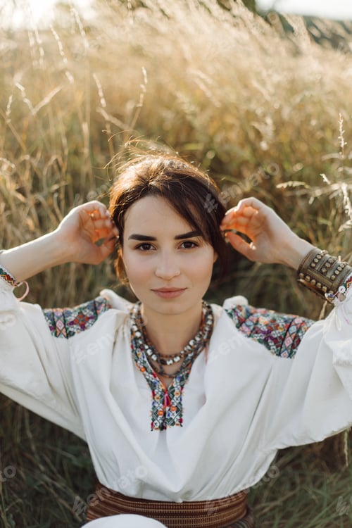 Preview: Young woman in traditional national embroidered shirt and skirt on nature at sunset.