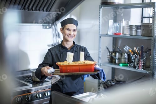Preview: Happy chef with tray of baked food in kitchen