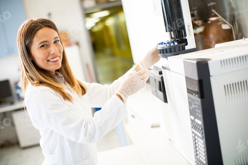 Preview: female scientist in a white lab coat putting vial with a sample for an analysis