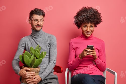 Preview: Positive addicted young woman uses mobile phone for browsing internet her boyfriend sits near holds
