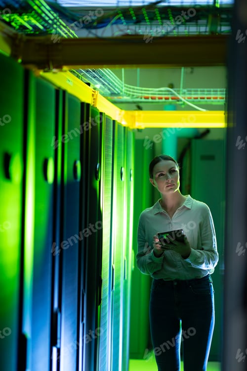 Preview: Caucasian female engineer using digital tablet while inspecting in computer server room