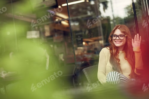 Preview: Beautiful Young Woman Greeting Friend While Sitting At The Table Behind Red And Green Lights. Copy