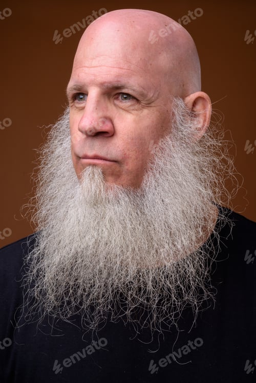 Preview: Mature bald man with long gray beard against brown background