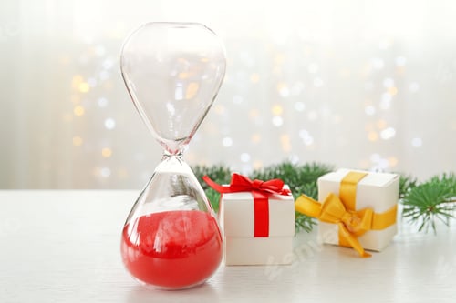 Preview: Hourglass with gifts and decor on table. Christmas countdown