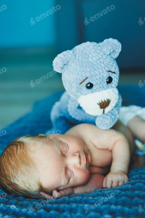 Preview: A newborn baby sleeps with a knitted teddy bear. Children's knitted toys. Baby sleep