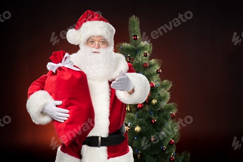 Preview: Santa Claus with red sack and gesturing with fir-tree behind