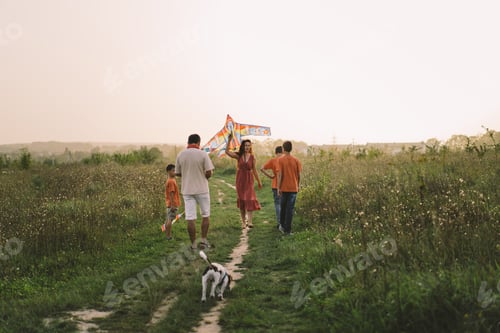 Preview: Happy family and children run on meadow with a kite in the summer on the nature.