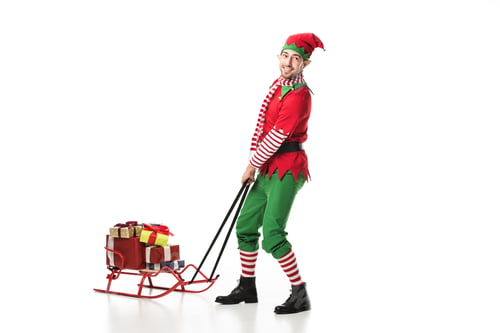 Preview: man in christmas elf costume crrying pile of presents isolated on white