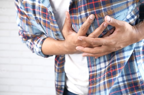 Preview: young man suffering pain in heart and holding chest with hand