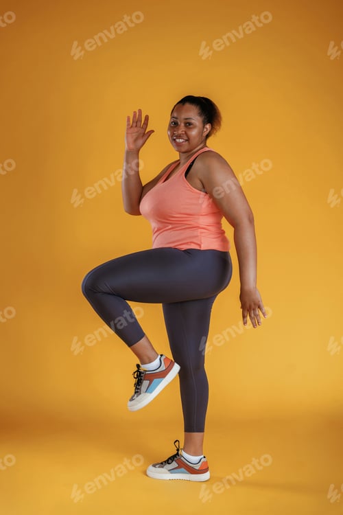 Preview: Doing fitness. African American woman is in the studio against yellow background