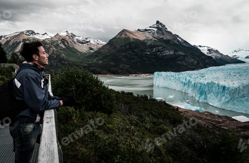 Preview: Hispanic male stands overlooking a tranquil lake surrounded by the majestic Perito Moreno glacier