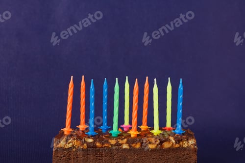 Visualização: Bolo de brownie de feliz aniversário com amendoim, caramelo salgado e velas coloridas acesas no