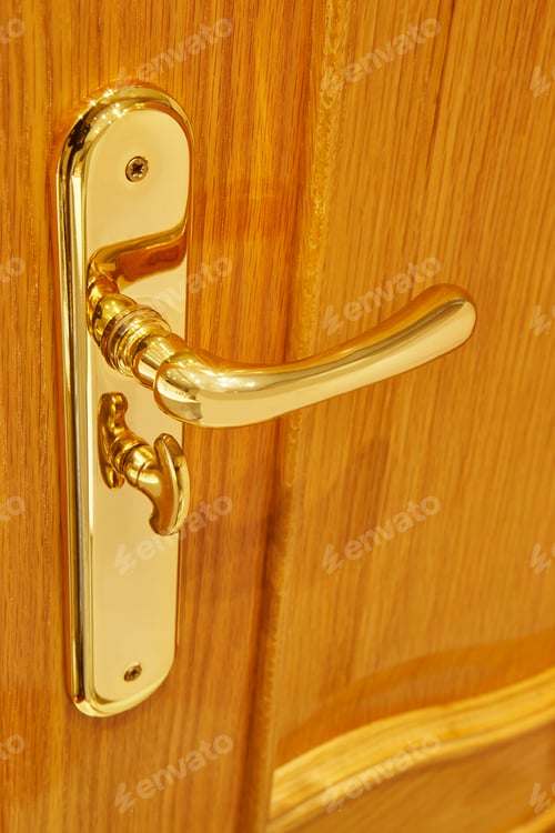 Preview: Golden door knob detail on an oak wooden door. Vertical