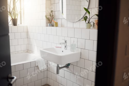 Preview: A clean and tidy bathroom inside a house. A basin, bath, with ceramic tiling and a round mirror han