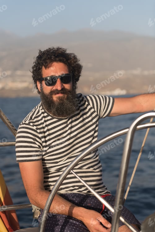 Preview: Smiling man holding steering wheel on yacht on water near quay