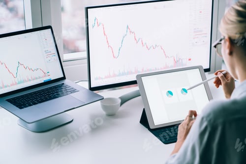 Preview: Crop female broker analyzing charts on tablet in office