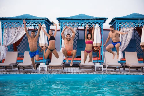 Preview: Happy young friends jumping in swimming pool