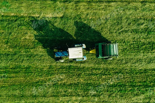 Preview: Aerial view of harvest field with tractor moving hay bale