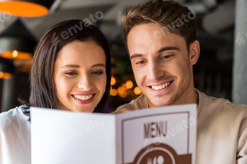 Preview: selective focus of happy man and cheerful woman holding menu