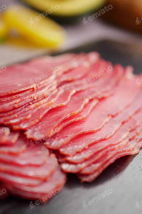 Preview: Slices of cured meat on a wooden board at a market stall