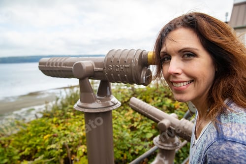Preview: Tourist woman looking through scope at ocean view point