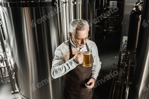 Preview: senior owner testing beer in professional brewery