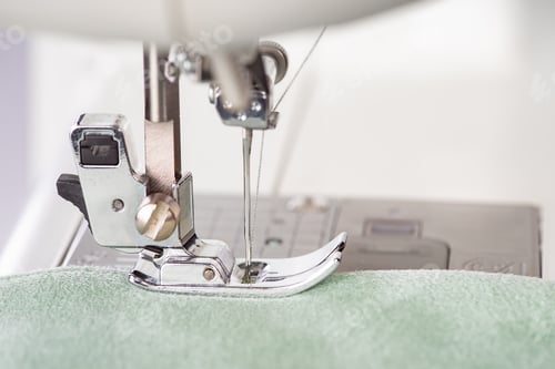 Preview: Modern sewing machine presser foot with green fabric and thread, closeup, macro