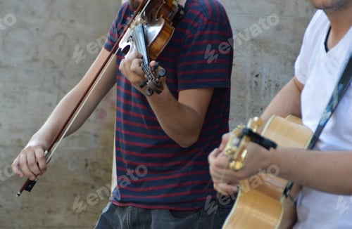 Preview: Midsection of men playing violin and guitar on street