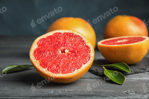 Preview: Whole and sliced tasty grapefruits on table