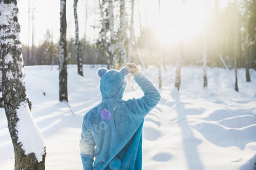 Preview: Shot of a person in a fluffy blue costume enjoying the sunlight in a forest in winter
