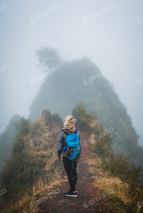 Preview: Woman hiker with backpack on the narrow misty path of mountain ridge on Santo Antao island, Cape