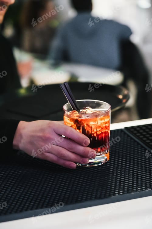 Preview: unrecognizable waiter preparing cocktails ready on the bar counter for delivery