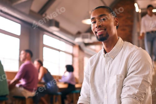 Preview: Portrait Of Smiling Businessman Working In Modern Office With Colleagues In Background