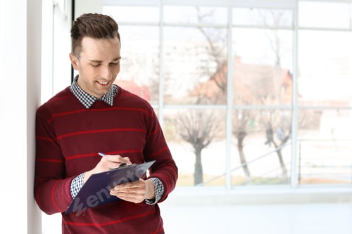 Preview: Male real estate agent with clipboard indoors