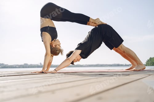 Preview: Man and woman doing yoga exercises by the water