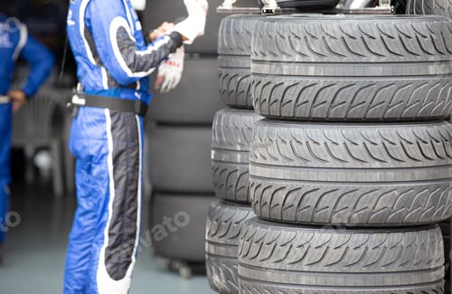 Preview: Racing Team Puts on Gloves Near Stack of Tires