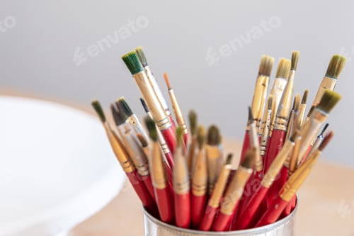 Preview: Close-up of red paint brushes in a metal jar.